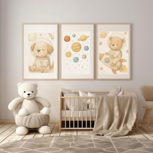 May include: Three framed nursery art prints with space-themed illustrations. One shows a dog astronaut, another depicts planets, and the third shows a bear astronaut on a rocket. The prints have a soft, pastel colour palette.