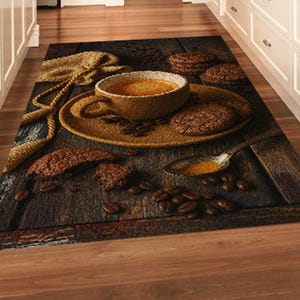 May include: A rectangular kitchen rug featuring a detailed image of a coffee cup, saucer, cookies, coffee beans, and a spoon on a wooden table. The rug has a brown and tan color scheme, with a rustic, inviting aesthetic.