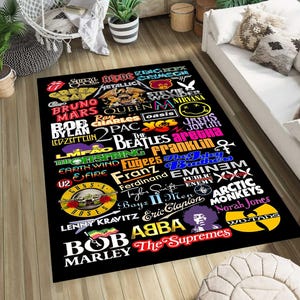 May include: Black rectangular rug with logos of music artists and bands in various colours. The rug features logos for The Beatles, Guns N' Roses, and Bob Marley. The rug is suitable for a living room.
