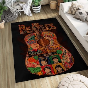 May include: A rectangular black area rug featuring a guitar design with the words "THE BEATLES" in brown. The guitar is decorated with colorful images and the faces of the Beatles.