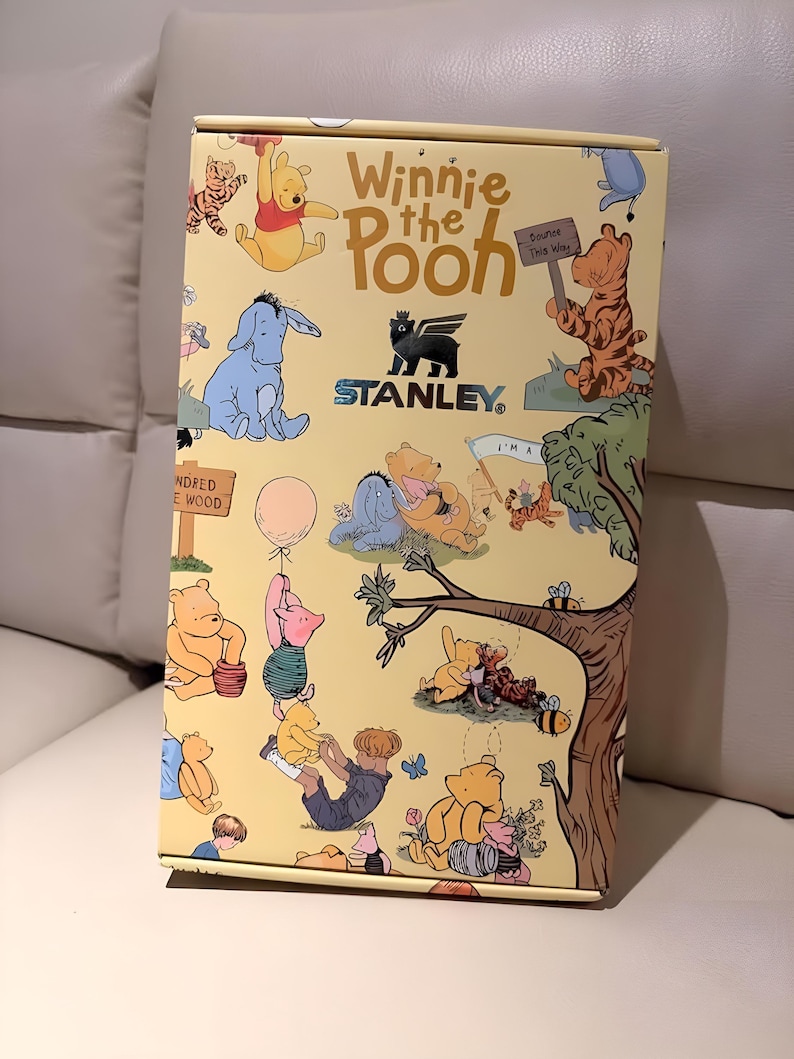 May include: A yellow box featuring illustrations of Winnie the Pooh characters, including Pooh, Eeyore, Tigger, and Piglet. The box has the text "Winnie the Pooh" and the Stanley logo. The box is decorated with images of the Hundred Acre Wood.