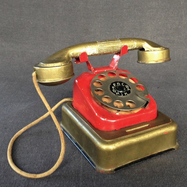 Red and gold antique tin toy telephone. Rescued vintage money box. Collectibles children phone souvenir.