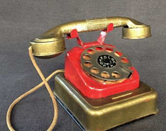 Red and gold antique tin toy telephone. Rescued vintage money box. Collectibles children phone souvenir.