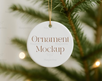 Könnte beinhalten: Ein weißer, runder Weihnachtsornament-Mockup mit den Worten "Ornament Mockup" in brauner Schrift. Der Ornament hängt an einem goldenen Faden vor einem verschwommenen Hintergrund eines Weihnachtsbaums mit weichen, leuchtenden Lichtern.