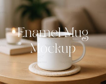 May include: A white enamel mug with a silver rim sits on a round, woven coaster. The mug is on a light brown wooden table. A lit candle and a book are in the background. The text "Enamel Mug Mockup" is on the mug.