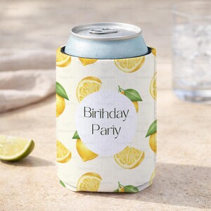 May include: A white can cooler with a lemon slice pattern and the words "Birthday Party" on a white circle. A light blue can sits inside the cooler. A lime wedge is in the foreground.