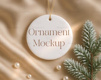Könnte beinhalten: Ein weißer, runder Ornament-Mockup mit dem Text "Ornament Mockup" in brauner Schrift. Das Ornament hängt an einem goldenen Faden. Der Hintergrund ist ein beiger Satin-Stoff mit Perlen und einem Tannenzweig.