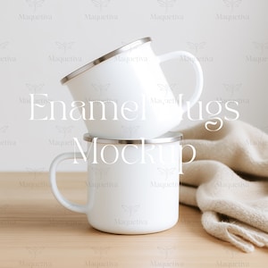 以下が含まれることがあります： 木製の表面に重ねられた、銀色の縁が付いた白いエナメルマグ2つ。マグは、湾曲したハンドルを備えたクラシックなデザインです。ベージュのスカーフが背景に掛けられています。「Enamel Mugs Mockup」というテキストが画像に重ねられています。
