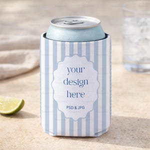 May include: A light blue can of soda in a striped blue and white can cooler. The cooler has a white label with the text "your design here" and "PSD & JPG". The can and cooler are on a light-colored surface.