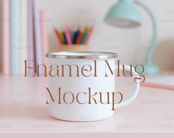 May include: A white enamel mug with a silver rim and handle. The words "Enamel Mug Mockup" are printed on the front. The mug is on a pink surface with a blurred background including a desk lamp and pencils.