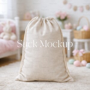Op de afbeelding: Een beige trekkoordzak-mockup, perfect voor het presenteren van productontwerpen. De zak is gemaakt van een textuurstof en staat rechtop op een lichtgekleurd tapijt. De woorden "Sack Mockup" staan op de voorkant.