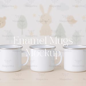 Könnte beinhalten: Drei weiße Emaille-Tassen mit silbernen Rändern und Griffen. Die Tassen stehen vor einem hellen Hintergrund mit einem skurrilen Design aus Zeichentricktieren und Bäumen. Der Text "Enamel Mugs Mockup" ist auf dem Bild überlagert.