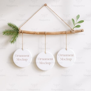 May include: A wooden branch with three round, white ornaments hanging from twine. The ornaments have the text "Ornament Mockup" printed on them. The branch is decorated with a sprig of green leaves and a small pine branch.