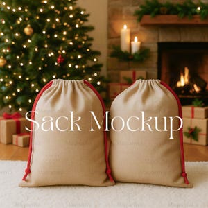 May include: Two beige drawstring sacks with red trim and drawstrings are displayed in front of a Christmas tree and fireplace. The text "Sack Mockup" is printed on the sacks. Presents are visible in the background.