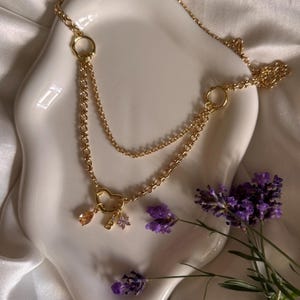 Collar de oro con dije de corazón. Cadena en capas, circonita cúbica y dije de la letra "Bella y Bella". Un regalo para ella.