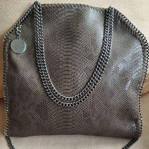 May include: A brown snakeskin-textured tote bag with a silver chain strap. The bag has a silver charm with the brand name on it.