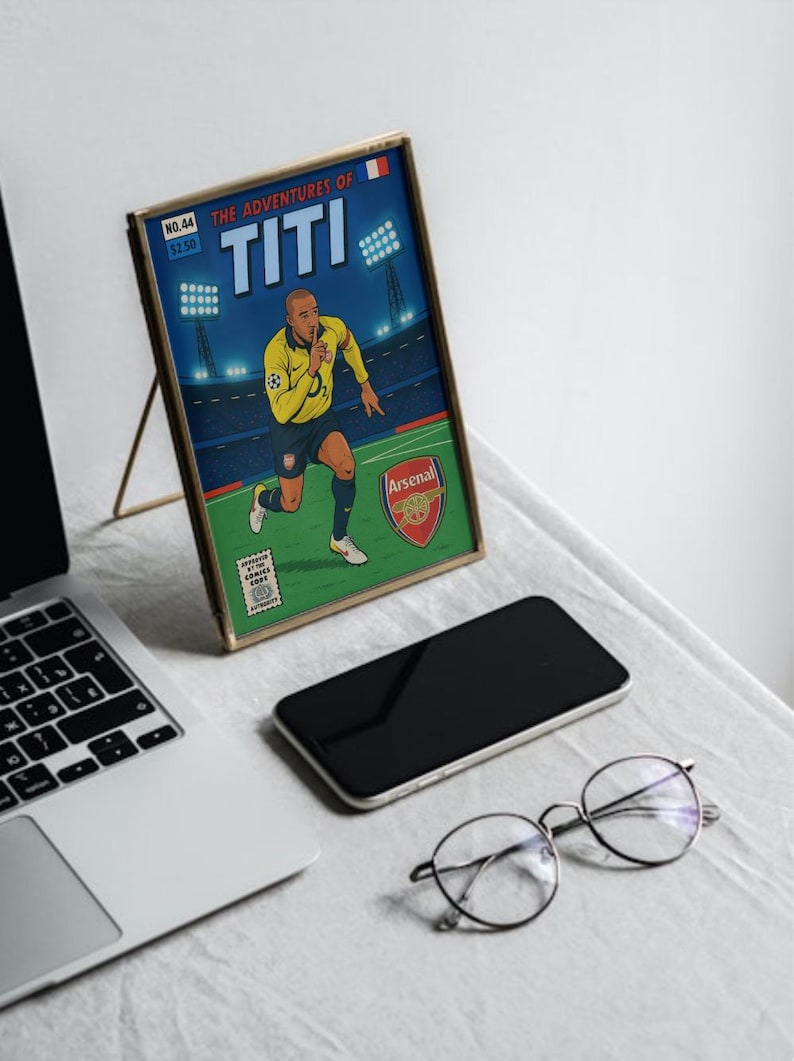 May include: A framed comic book cover featuring a cartoon illustration of a soccer player in a blue and yellow jersey with the text "THE ADVENTURES OF TITI" and "Arsenal" on the cover.