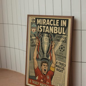 May include: Framed poster with a vintage comic book style. The artwork features a soccer player holding a trophy, with the headline "Miracle in Istanbul." The poster has a brown frame and is set against a white tile background.