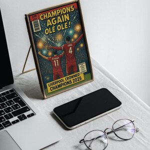 May include: A comic book cover with a gold frame featuring two soccer players celebrating a victory. The cover reads "Champions Again Ole Ole!" and "Liverpool Crowned Champions 2025".