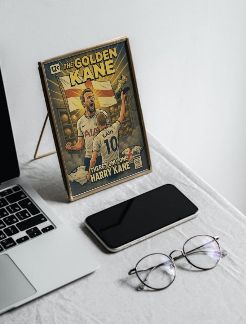 Puede incluir: Obra de arte enmarcada estilo c&oacute;mic con el texto "The Golden Kane" y "There's Only One Harry Kane". La obra representa a un jugador de f&uacute;tbol sosteniendo un trofeo. Tambi&eacute;n se ven un port&aacute;til, un tel&eacute;fono y gafas.