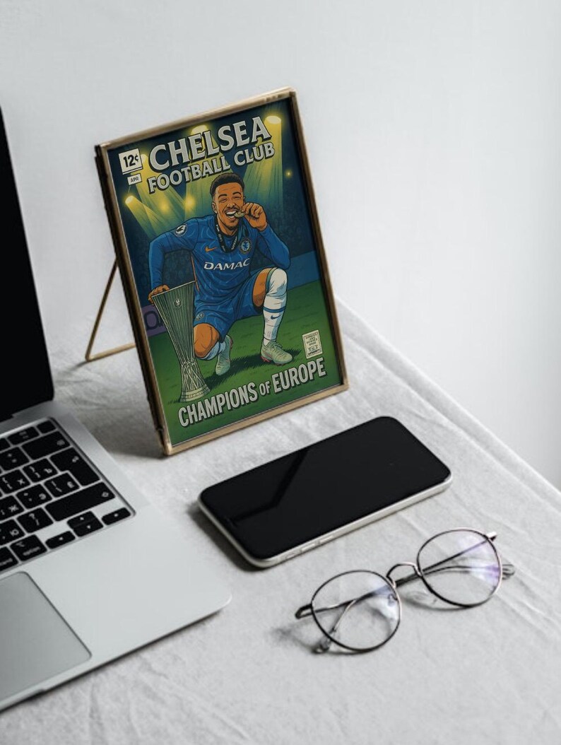 May include: A framed illustration of a Chelsea Football Club player celebrating with a trophy. The artwork is in a comic book style, with the text "CHELSEA FOOTBALL CLUB" and "CHAMPIONS OF EUROPE". The frame is gold-coloured.