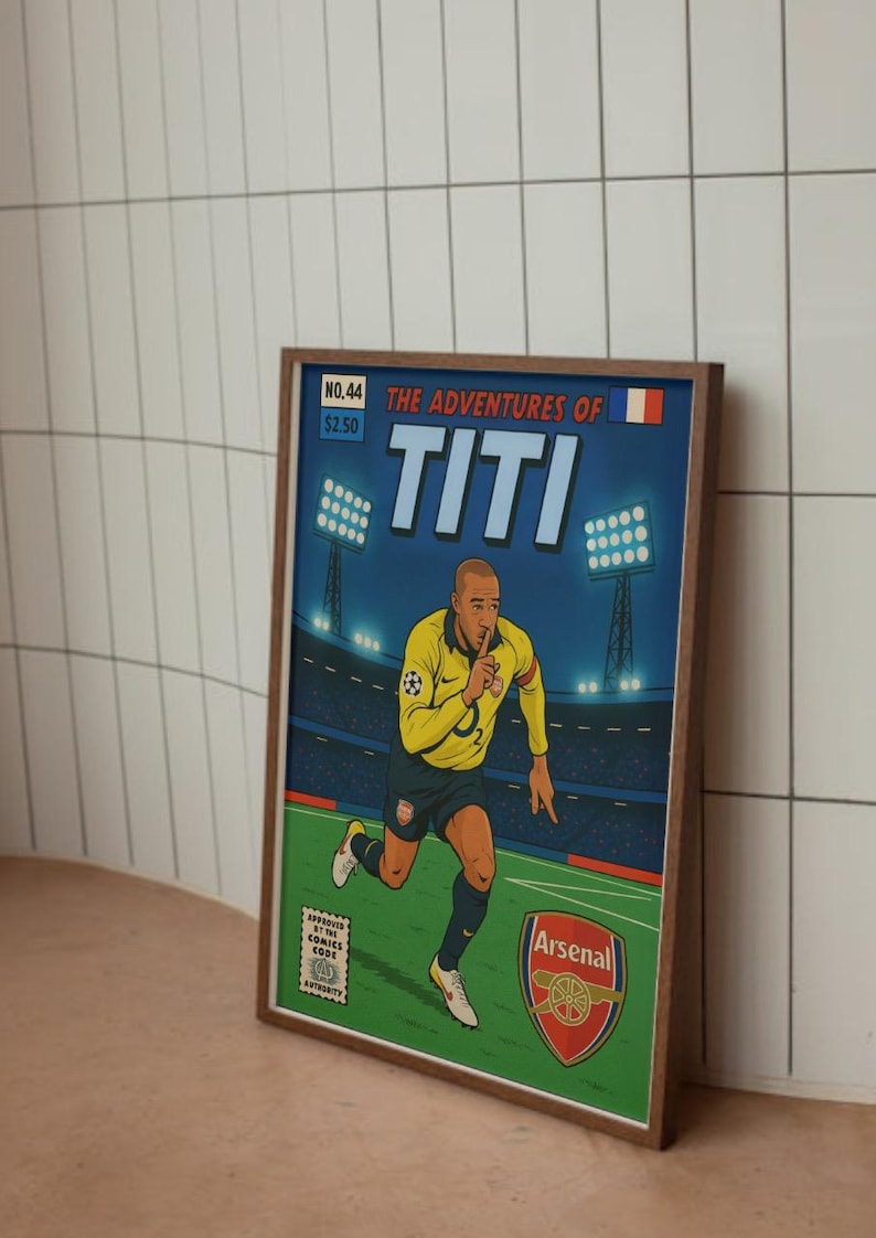 May include: A comic book cover featuring a cartoon illustration of a soccer player in a yellow and blue jersey with the number 3 on the back. The cover is titled "The Adventures of Titi" and features the Arsenal logo. The comic book is framed in a brown wood frame.