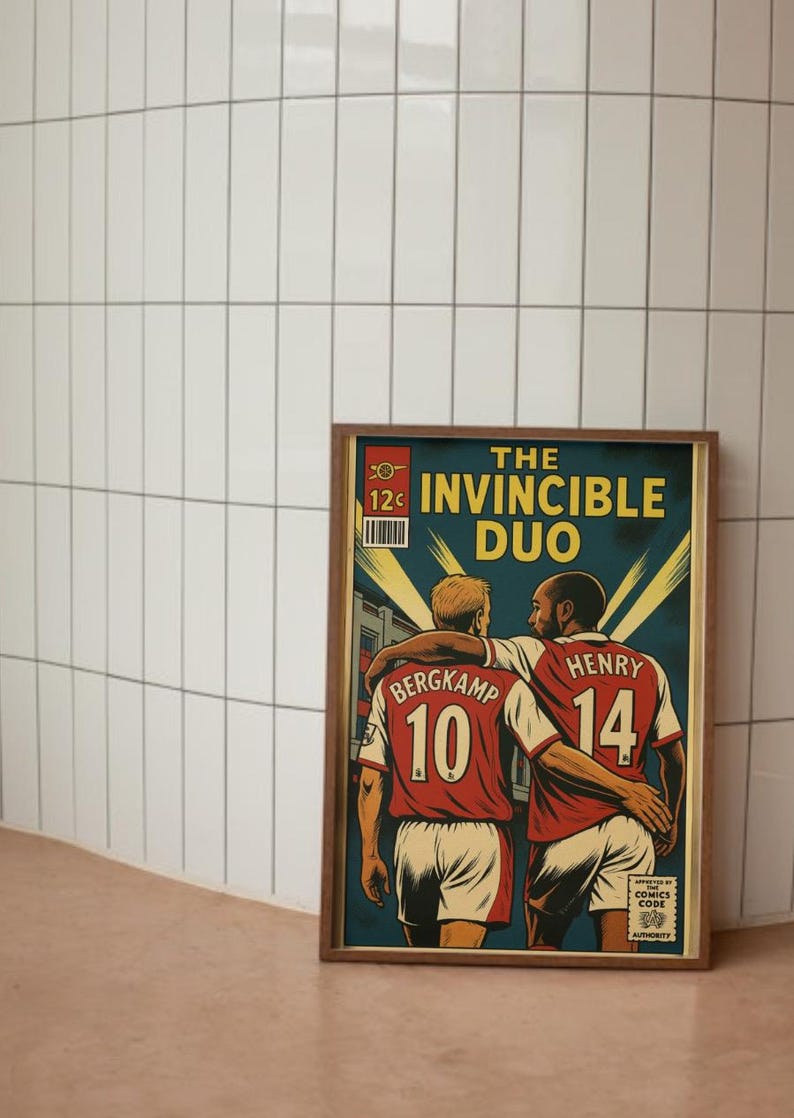 Peut inclure: Une affiche encadr&eacute;e de style bande dessin&eacute;e repr&eacute;sentant deux joueurs de football en maillots rouges avec les num&eacute;ros 10 et 14. Le texte dit "THE INVINCIBLE DUO" dans un style de bande dessin&eacute;e vintage.