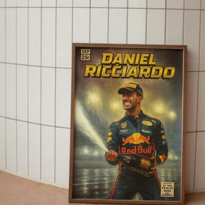 Puede incluir: Un p&oacute;ster enmarcado con Daniel Ricciardo, un piloto de F&oacute;rmula 1, celebrando con champ&aacute;n. El p&oacute;ster tiene un estilo de c&oacute;mic vintage con el texto "DANIEL RICCIARDO" en amarillo. El logotipo de Red Bull es visible.