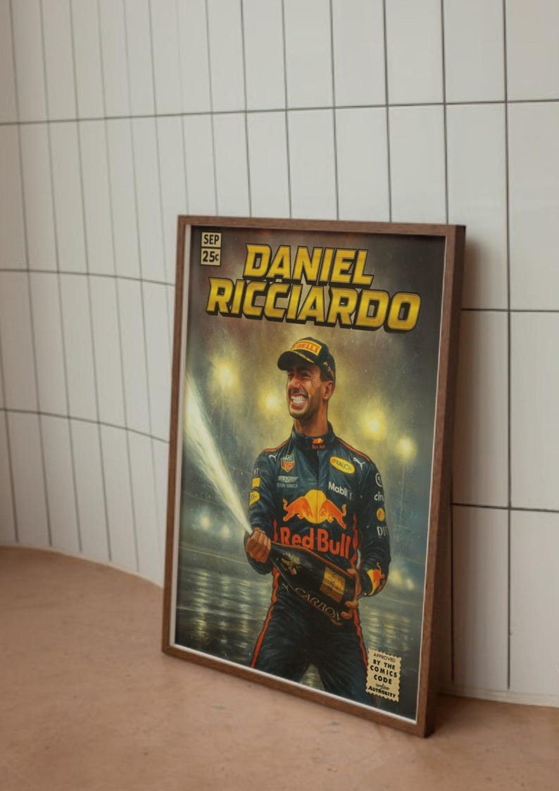 Puede incluir: Impresi&oacute;n enmarcada al estilo c&oacute;mic que presenta a Daniel Ricciardo celebrando con champ&aacute;n. La obra de arte tiene una est&eacute;tica vintage con el texto "DANIEL RICCIARDO" en amarillo. La impresi&oacute;n est&aacute; en un marco de madera marr&oacute;n.