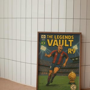 K&ouml;nnte beinhalten: Ein gerahmtes Poster mit einer Comic-Illustration eines Fu&szlig;ballspielers in einem blau-roten Trikot, der einen goldenen Fu&szlig;ball h&auml;lt. Das Poster tr&auml;gt den Text "The Legends Vault R9" und "10&cent; 2002" in der oberen linken Ecke.