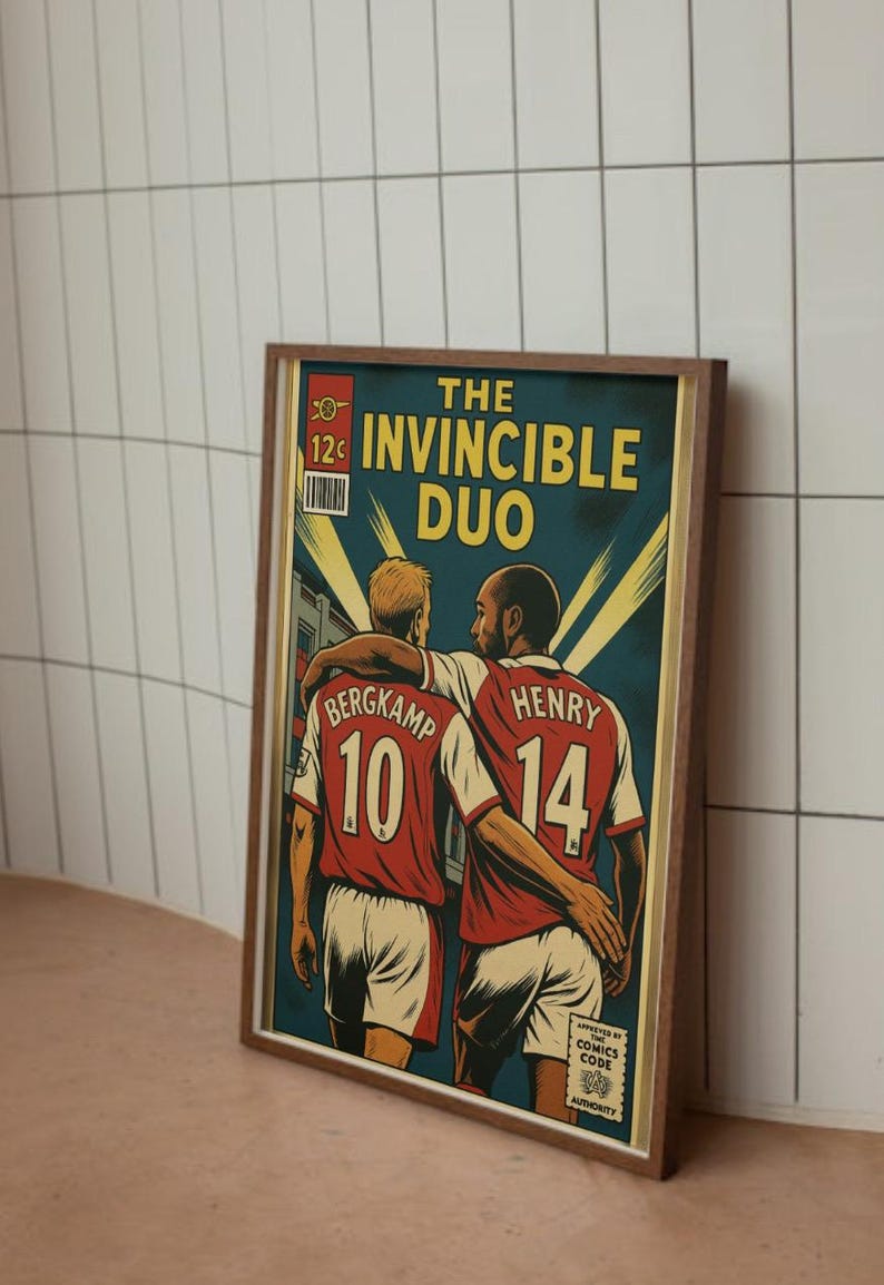 Peut inclure: Impression de style bande dessin&eacute;e encadr&eacute;e repr&eacute;sentant deux joueurs de football en maillots rouge et blanc, avec le texte "THE INVINCIBLE DUO". Un joueur porte le num&eacute;ro 10, l'autre le 14. L'impression a une esth&eacute;tique vintage.