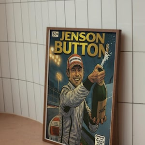 May include: Framed comic book style print featuring Jenson Button celebrating with champagne. The print has a vintage look with the text "Jenson Button" in gold lettering. The print is in a brown wooden frame.