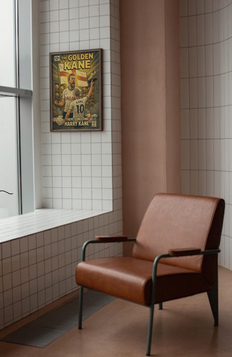 Puede incluir: Un sill&oacute;n de cuero marr&oacute;n con patas y reposabrazos de metal. Un p&oacute;ster enmarcado en la pared presenta una ilustraci&oacute;n de estilo c&oacute;mic de un jugador de f&uacute;tbol con el texto "THE GOLDEN KANE". La habitaci&oacute;n tiene baldosas blancas y una pared rosa.