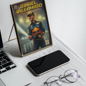 Puede incluir: Una impresi&oacute;n enmarcada de estilo c&oacute;mic con Daniel Ricciardo, un piloto de F&oacute;rmula 1, celebrando con champ&aacute;n. La impresi&oacute;n est&aacute; en un marco dorado, sobre una mesa con un port&aacute;til, un smartphone y gafas. El texto "DANIEL RICCIARDO".