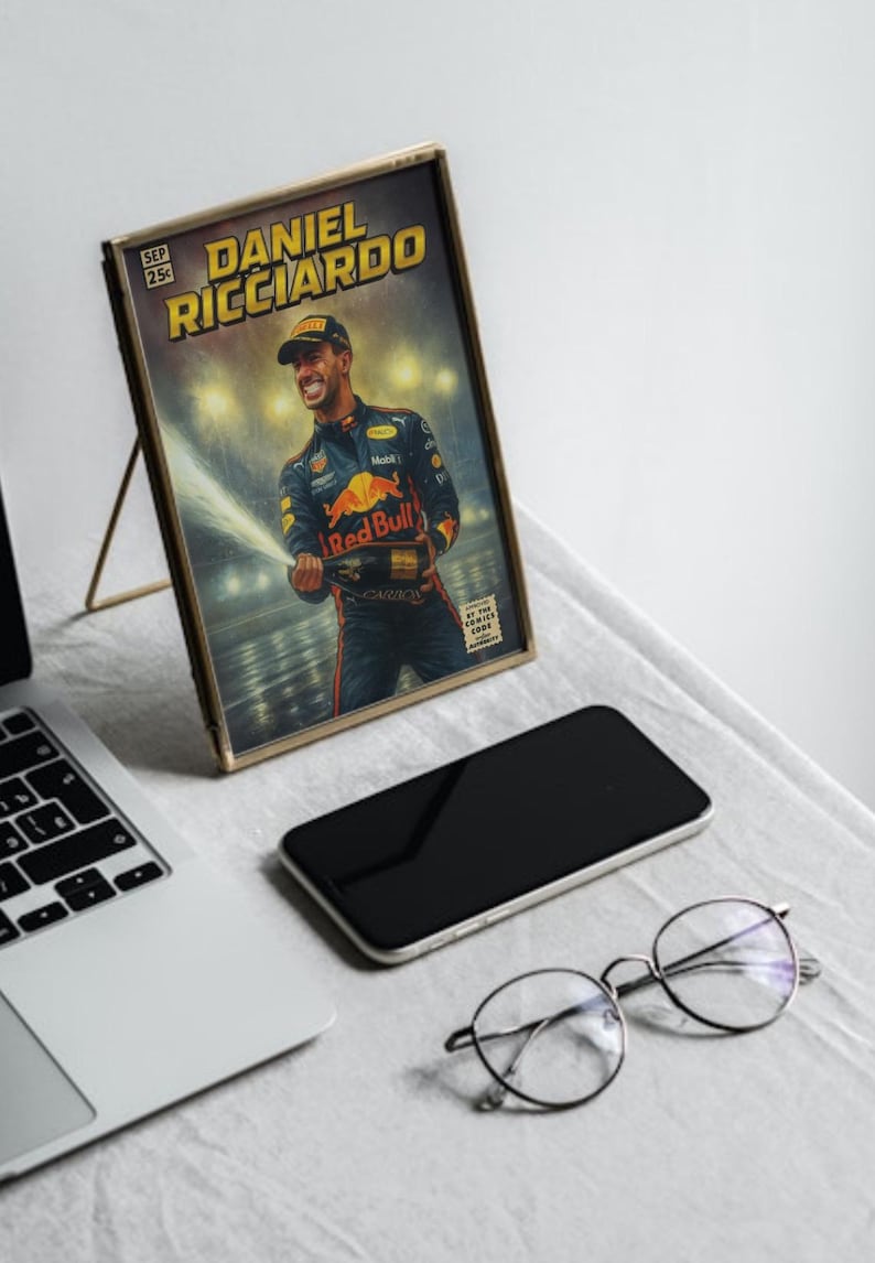 Puede incluir: Una impresi&oacute;n enmarcada de estilo c&oacute;mic con Daniel Ricciardo, un piloto de F&oacute;rmula 1, celebrando con champ&aacute;n. La impresi&oacute;n est&aacute; en un marco dorado, sobre una mesa con un port&aacute;til, un smartphone y gafas. El texto "DANIEL RICCIARDO".