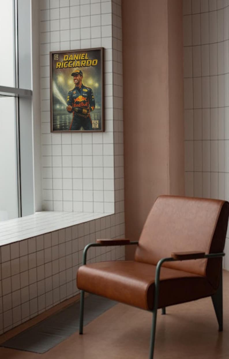 Puede incluir: Un p&oacute;ster enmarcado con Daniel Ricciardo, piloto de F&oacute;rmula 1, sosteniendo una botella de champ&aacute;n. El p&oacute;ster tiene un estilo vintage con un marco marr&oacute;n y est&aacute; colgado en una pared de azulejos blancos. Cerca hay un sill&oacute;n de cuero marr&oacute;n con patas de metal.