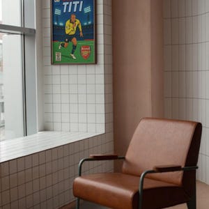 May include: A framed comic book cover featuring a soccer player in a yellow jersey with the text "THE ADVENTURES OF TITI" and "Arsenal" on the cover.