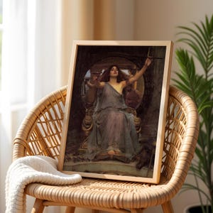 May include: A framed print of a classical painting depicting a woman in a flowing gown seated on a throne. The artwork features muted tones of blue, brown, and gold, with the woman holding a chalice and a wand. The frame is made of light-colored wood.