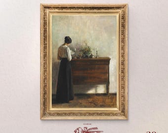 May include: A framed oil painting of a woman in a white blouse and black skirt standing in front of a wooden dresser. The woman is reading a book. The painting is in a gold frame.