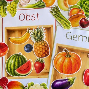 May include: Educational charts featuring colorful illustrations of various fruits and vegetables. The left chart is labeled Obst and displays a banana, pineapple, blueberry, strawberry, watermelon, and mango. The right chart is labeled Gemu.