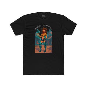 May include: Black t-shirt featuring a colorful illustration of a cowgirl holding a gun, with the text "Sexy and From Texas." The design includes a saloon backdrop. The shirt is made of a soft, comfortable material.