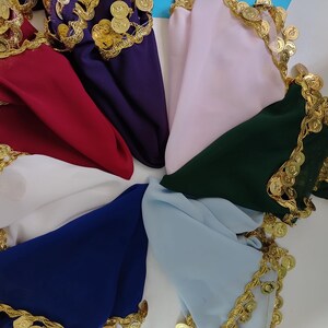May include: A collection of seven triangular scarves in red, purple, light pink, dark green, light blue, royal blue, and white. Each scarf features a decorative gold-toned metallic coin trim along the edges, creating a shimmering effect.