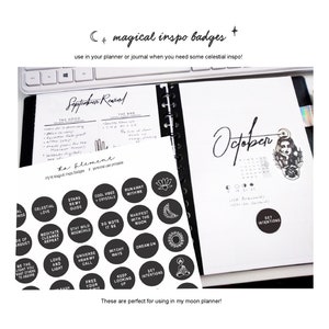 May include: A planner with a black spiral binding, open to a page with the month of October. A sheet of black circular stickers with white celestial-themed text and graphics is visible. Text on the stickers includes "Dream On" and "Set Intentions".