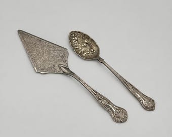Juego de utensilios de servir vintage ornamentados: pala para pastel y cuchara para fruta en tono plateado, vajilla con relieve floral.