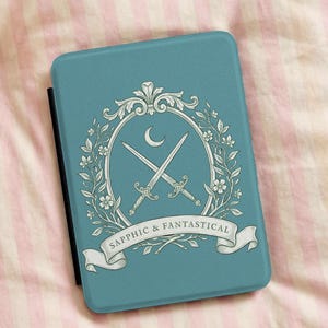 May include: A teal e-reader case featuring a white floral design with crossed swords and a crescent moon. The text "Sapphic & Fantastical" is displayed on a banner below the design. The case is rectangular and has a black spine.
