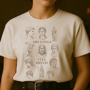May include: Cream-colored t-shirt featuring a collection of classical busts and statues in a minimalist style. The shirt includes the phrases "ARS LONGA" and "VITA BREVIS" in a simple, elegant font. A stylish and artistic garment.