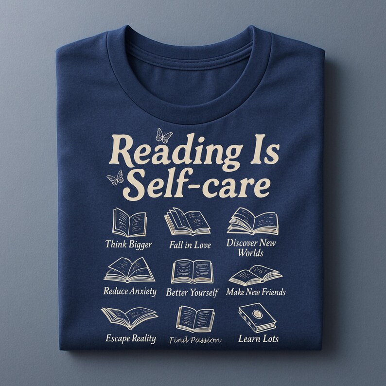 Puede incluir: Camiseta azul marino con el texto "Reading Is Self-care" e ilustraciones de libros. La camiseta tambi&eacute;n incluye las frases "Think Bigger", "Fall in Love", "Discover New Worlds", "Reduce Anxiety", "Better Yourself", "Make New Friends", "Escape Reality", "Find Passion" y "Learn Lots".