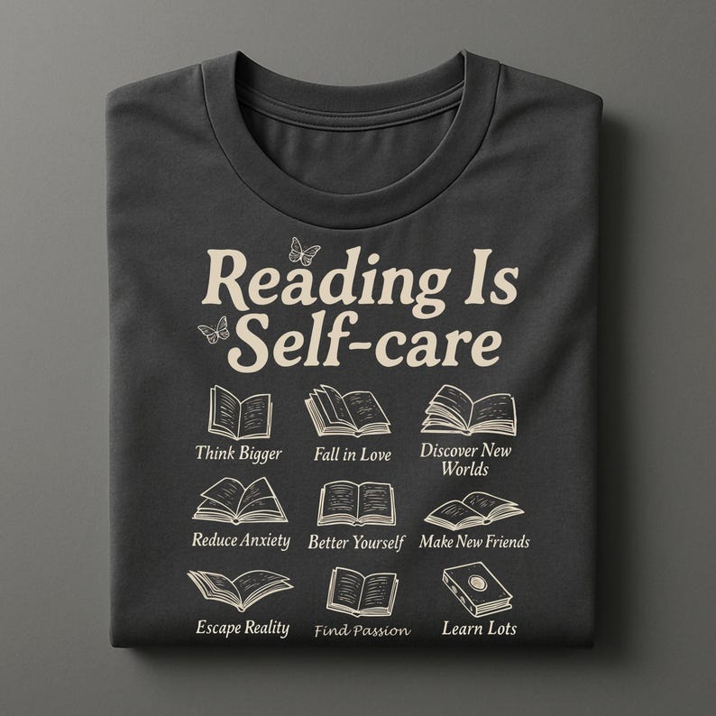 Puede incluir: Camiseta gris oscuro con el texto "Reading Is Self-care" e ilustraciones de libros. Debajo, las frases "Think Bigger", "Fall in Love", "Discover New Worlds", "Reduce Anxiety", "Better Yourself", "Make New Friends", "Escape Reality", "Find Passion" y "Learn Lots".