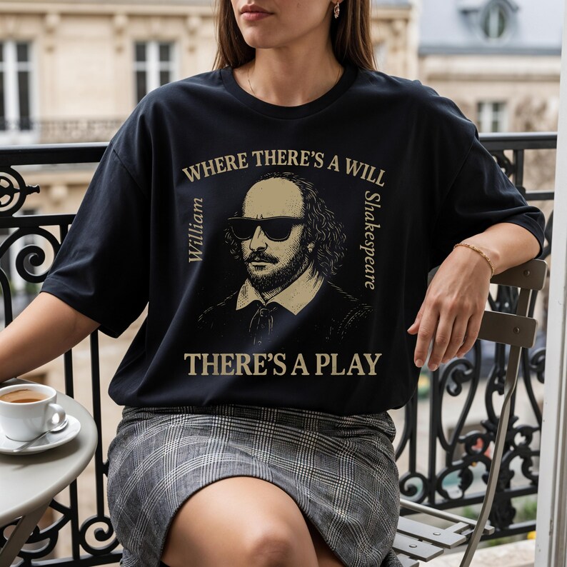 May include: Black t-shirt with a sepia image of William Shakespeare in sunglasses. The text reads "WHERE THERE'S A WILL THERE'S A PLAY", with "William" and "Shakespeare" on either side of the image. The shirt is worn by a person.