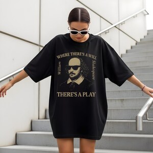 May include: Black oversized t-shirt with a graphic of William Shakespeare in sunglasses. The text reads "WHERE THERE'S A WILL THERE'S A PLAY", with "William" and "Shakespeare" on either side. The shirt is being worn by a person.